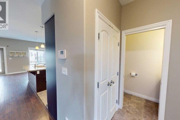Hallway with a closed bi-fold closet door and an open doorway revealing a toilet. - B, 13022 91a Street, Grande Prairie