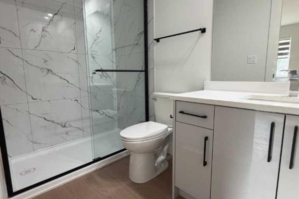 Ensuite bathroom with a glass-enclosed shower with marble-patterned tiles and a white toilet. - C, 9403 103 Avenue, Grande Prairie