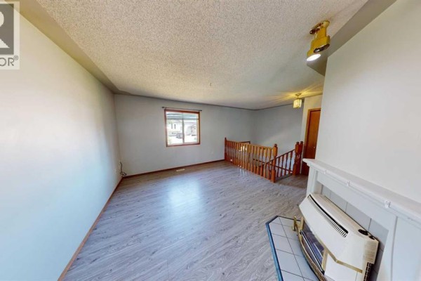 Living room with light grey laminate flooring, white walls, and a gas fireplace. - B, 9408 100 Avenue, Grande Prairie
