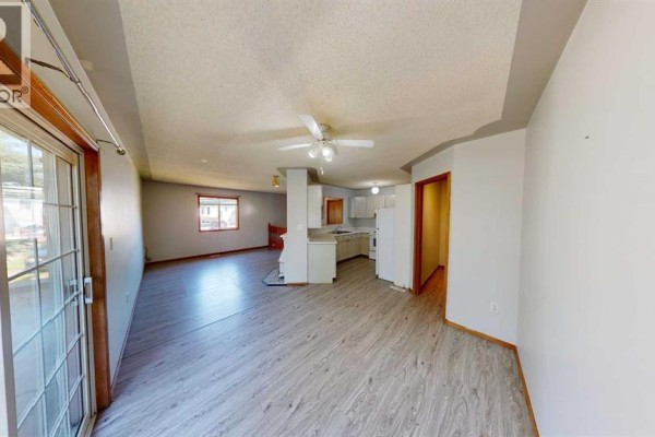 Open-concept living area, kitchen, and dining space with light grey laminate flooring. - B, 9408 100 Avenue, Grande Prairie