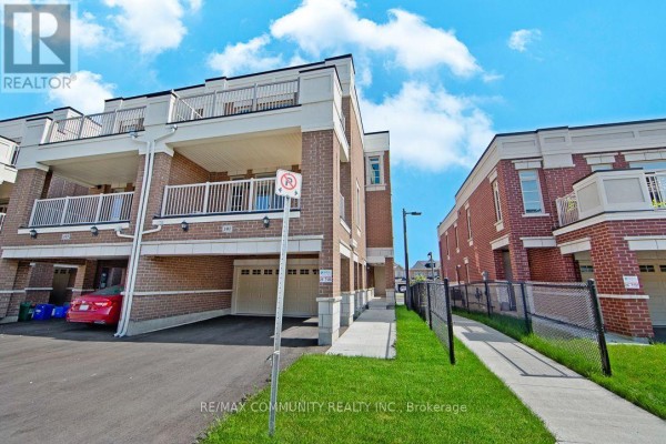 Exterior view of a townhouse complex with a sidewalk, grass, and chain-link fence. - B - 101 Luzon Avenue, Markham