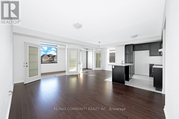 Open-concept living area with dark hardwood floors, dark kitchen cabinets, and glass doors. - B - 101 Luzon Avenue, Markham