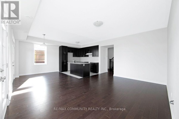 Living and kitchen area with dark hardwood floors, dark kitchen island and cabinets, and a staircase. - B - 101 Luzon Avenue, Markham