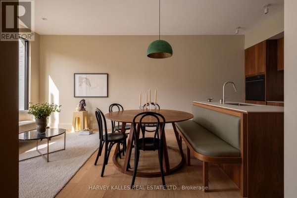 Dining area with a round wooden table, black chairs, and green banquette seating. - B - 157 Hallam Street, Toronto