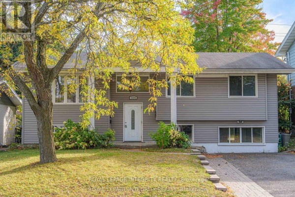 Front exterior of a grey bungalow with a large tree in the yard. - B - 1896 Featherston Drive, Ottawa