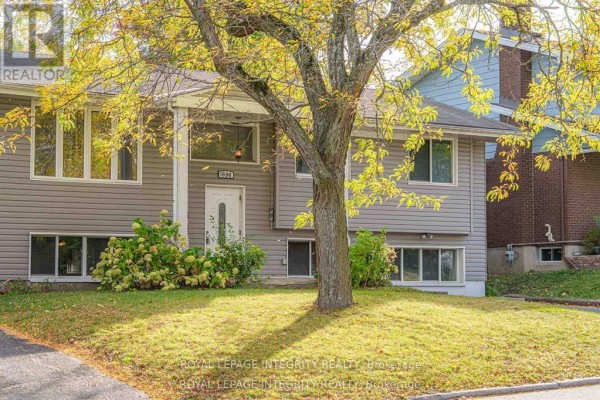 Front entrance of a grey house with mature trees and fall foliage. - B - 1896 Featherston Drive, Ottawa