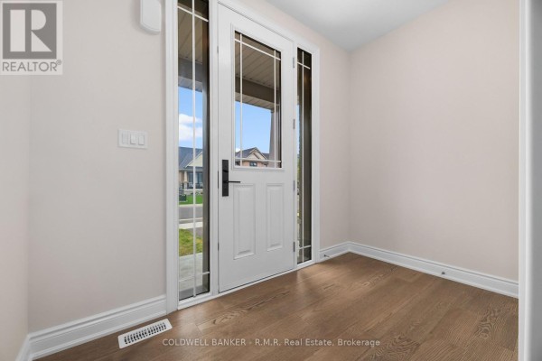 View through a glass front door showing an interior foyer with hardwood floors. - B - 434 Orchard Avenue S, Cobourg