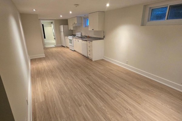 Bright basement living area with light wood laminate flooring and a small white kitchen. - B - 50 Elmer Avenue, Orillia