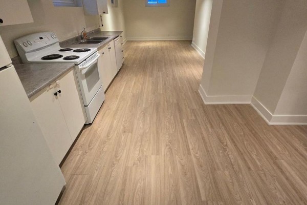 Close-up of a white stove and sink area with white cabinetry and light wood laminate flooring. - B - 50 Elmer Avenue, Orillia