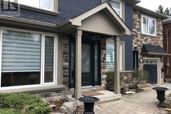 Close-up of the front entrance porch with stone accents and a dark grey door. - B - 55 Addington Avenue, Toronto