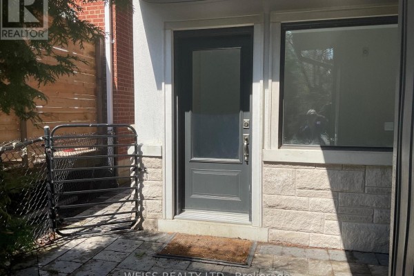 A grey front door with a glass pane, surrounded by stone and brick exterior. - B - 55 Addington Avenue, Toronto
