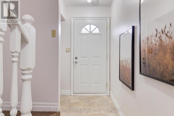 View of an entryway with a white door, beige tile floor, and white railings for stairs. - B - 56 Harris Avenue, Brantford