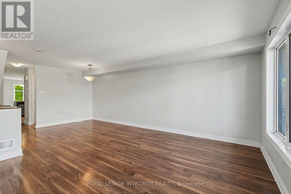 Spacious living room with wood flooring and large windows on two walls. - B - 621 Chapman Mills Drive, Ottawa