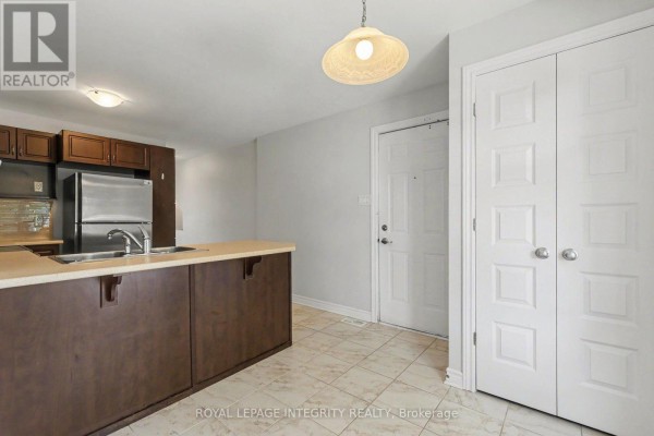 Kitchen with dark wood cabinets, stainless steel appliances, and a large white double door closet. - B - 621 Chapman Mills Drive, Ottawa