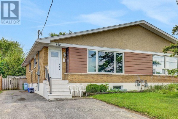 Front exterior of a yellow brick and brown siding house with a white door and steps. - B - 892 Baseline Road, Ottawa