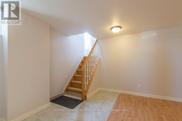 Interior view of a staircase leading down to a tiled and wood-floored area. - B - 892 Baseline Road, Ottawa