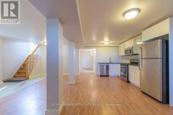 Basement living area with wood floors, kitchenette, stainless steel appliances, and view of hallway. - B - 892 Baseline Road, Ottawa