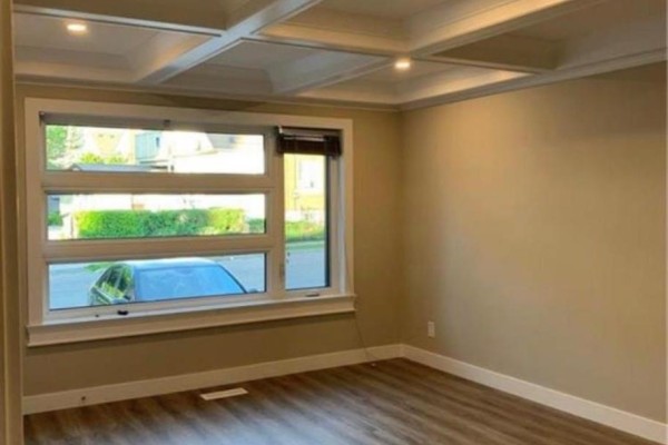 Empty room with large windows, beige walls, and wood-look laminate flooring. - B - 9 York Street, Kitchener