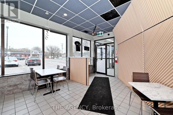 Interior view of restaurant seating area with tables, chairs, and a counter, looking towards entrance. - B-1 - 1540 Dundas Street E, Whitby