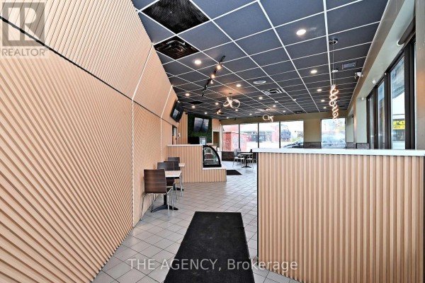 Interior view of restaurant with wood-slat accent walls, counter area, and seating visible. - B-1 - 1540 Dundas Street E, Whitby