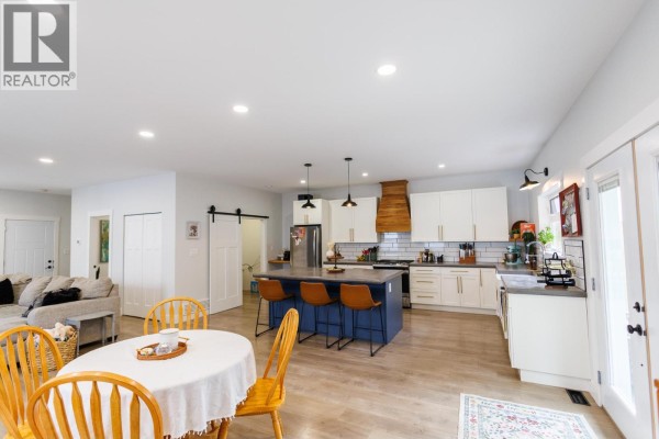 Open concept living area with a white kitchen, blue island with bar stools, dining table, and living room furniture. - B 4005 Benner Street, Terrace
