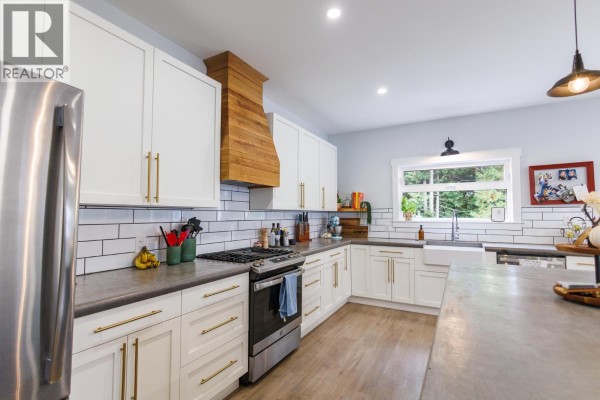 Kitchen with white cabinets, gray countertops, stainless steel range, and subway tile backsplash with a wooden range hood. - B 4005 Benner Street, Terrace