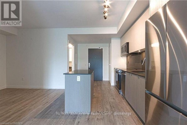 Open-concept living area and kitchen with light wood floors and grey island. - B0721 - 133 Bronte Road, Oakville