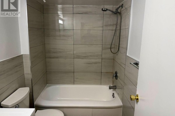 Small bathroom with a bathtub, showerhead, and white tiled walls. - B1 - 1582 Bathurst Street, Toronto