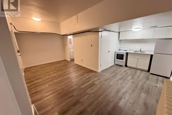 Studio apartment kitchen area with white cabinets, a white stove, and a white refrigerator. - B1 - 1582 Bathurst Street, Toronto