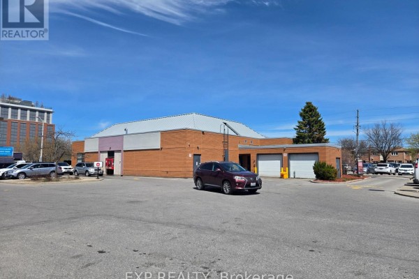 Commercial building with brick exterior and two large garage doors on a sunny day. - B10 - 4779 Steeles Avenue E, Toronto