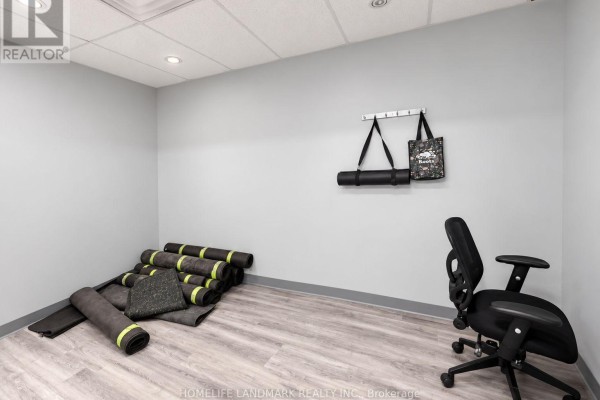 Small room with light gray walls, stacked yoga mats, and an office chair. - B101 - 7155 Woodbine Avenue, Markham