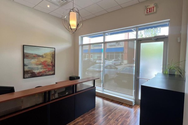 Reception desk area with wooden floor, large windows, and abstract art on the wall. - B108 - 11685 Yonge Street, Richmond Hill