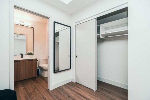 Hallway with a large mirror, a sliding closet door revealing shelves and hanging space, and an open doorway to a bathroom. - B11 45815 Princess Avenue, Chilliwack Downtown, Chilliwack