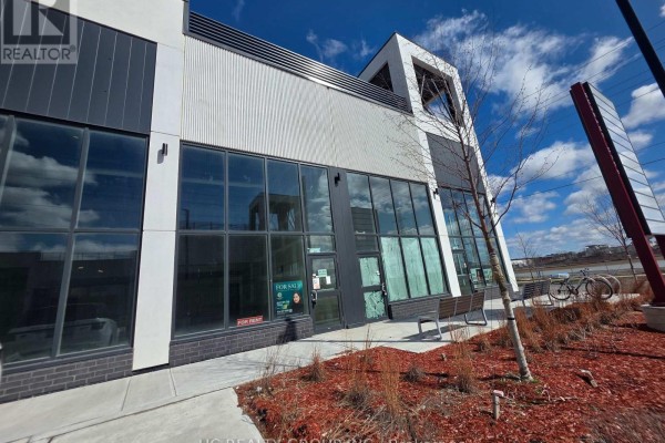 Close-up of a commercial building facade with grey and white panels and large windows. - 33 - 3101 Kennedy Road, Toronto