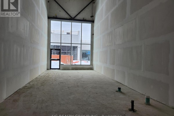 Unfinished interior commercial space with drywall walls and a large front window. - 33 - 3101 Kennedy Road, Toronto