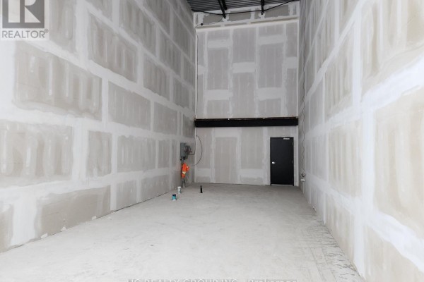 View of an empty interior commercial space with drywall walls and a dark door. - 33 - 3101 Kennedy Road, Toronto