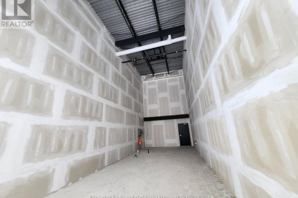 Wide shot of unfinished commercial interior with high ceilings and exposed pipes. - 33 - 3101 Kennedy Road, Toronto