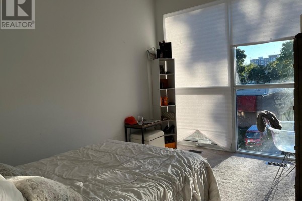 Bedroom with a bed, shelving unit, and a window with blinds. - B2 - 3 Falaise Road, Toronto