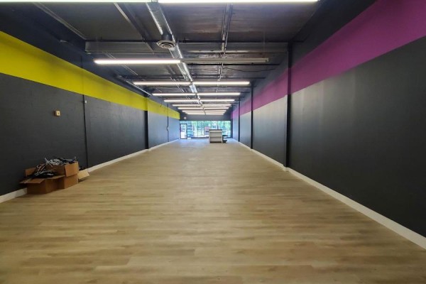 Empty commercial interior with light wood-look flooring and dark walls. - B2 - 39 Orfus Road, Toronto