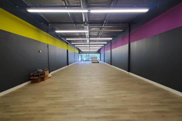 Unoccupied retail space with tan laminate flooring and yellow and pink accent walls. - B2 - 39 Orfus Road, Toronto