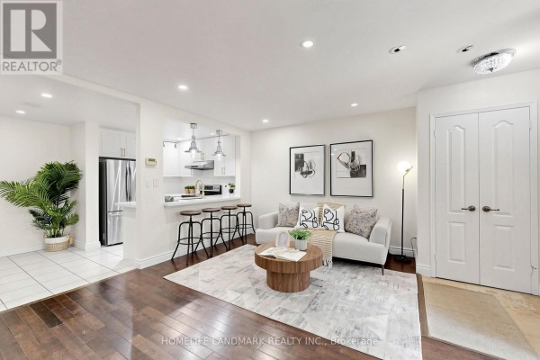 Living room with a sofa, coffee table, and view into the kitchen and hallway. - B29 - 108 Finch Avenue W, Toronto