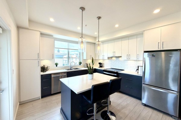 Modern apartment kitchen with dark gray cabinets, white countertops, stainless steel appliances, and pendant lights. - B316 20834 80 Avenue, Langley