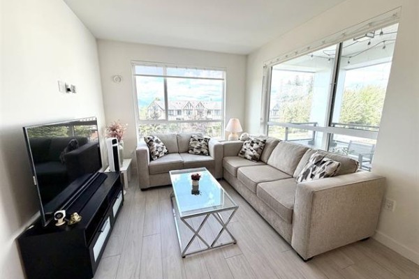Apartment dining area with a glass table and gray chairs, adjacent to a modern kitchen with an island. - B316 20834 80 Avenue, Langley