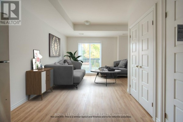 Living room with light wood floors, grey sofa, round coffee table, and a sliding glass door. - B5 - 374 Prospect Avenue, Kitchener
