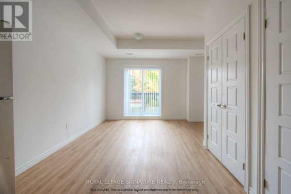 Empty living space with light wood floors, white walls, and double white doors on the right. - B5 - 374 Prospect Avenue, Kitchener