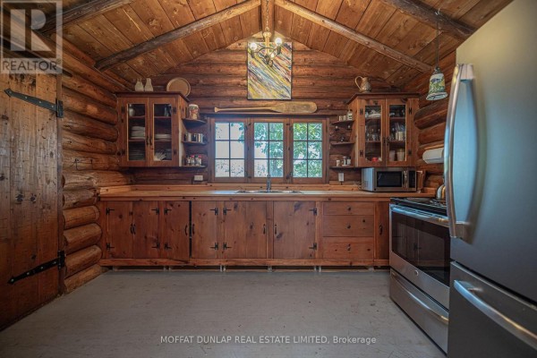 Log cabin kitchen with wood cabinets, stainless steel appliances, and a large window. - B691 Island Island, The Archipelago