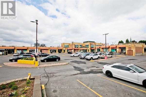 Parking lot with multiple vehicles and commercial buildings in the background. - B8a - 4227 Sheppard Avenue E, Toronto