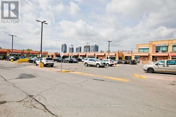 Wide view of parking area with several cars and storefronts visible. - B8a - 4227 Sheppard Avenue E, Toronto