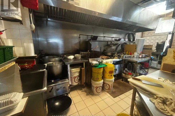 Commercial kitchen with stainless steel appliances and various cooking equipment. - B8a - 4227 Sheppard Avenue E, Toronto