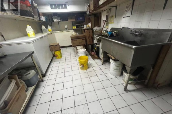Interior view of kitchen area with sinks, storage, and cleaning supplies. - B8a - 4227 Sheppard Avenue E, Toronto